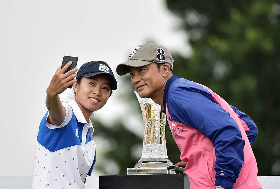 著名影星任达华在职业业余配对赛中与年轻球员亲切自拍，笑容灿烂，展现跨界交流的轻松氛围