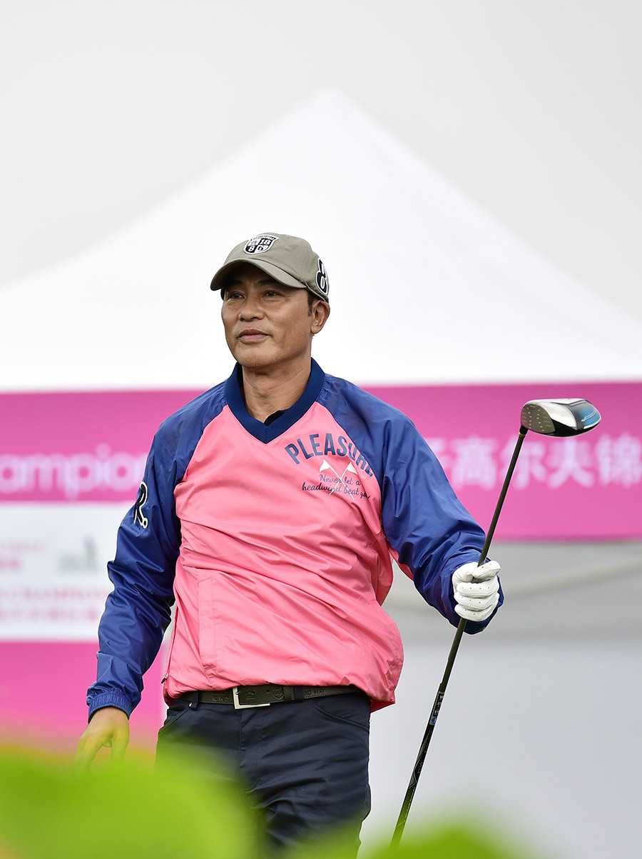 任达华完成一次优雅流畅的收杆动作，身体姿态平衡而稳定，目光望向远处小白球的飞行轨迹