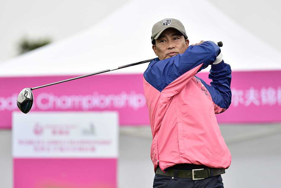 任达华以一身时尚粉色运动装亮相球场，在绿茵背景下格外醒目，正与身旁友人愉快交流