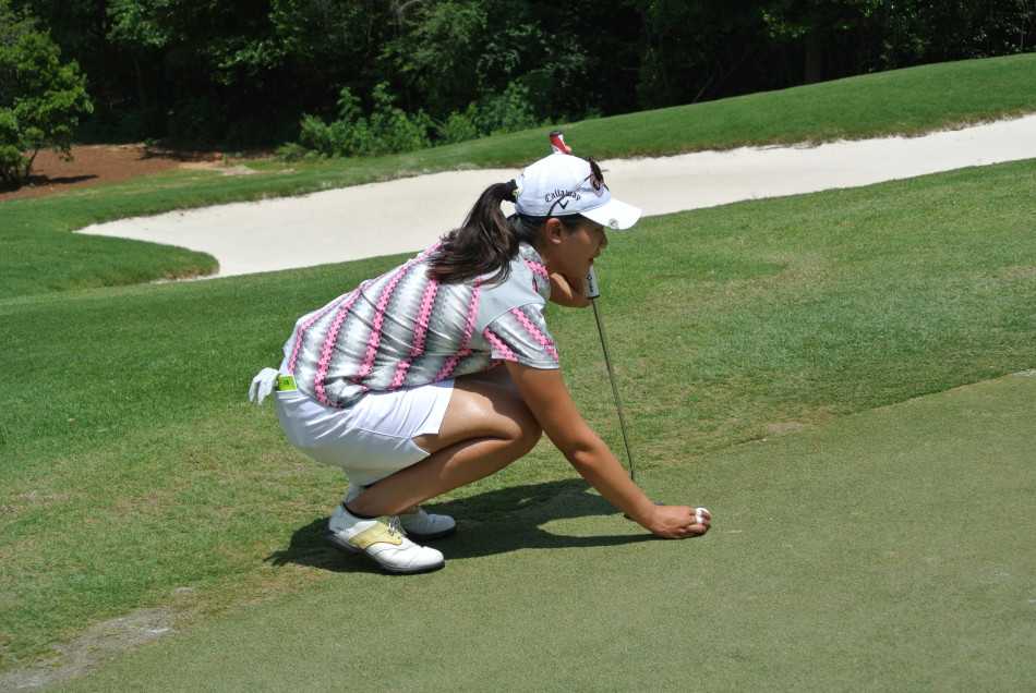 果岭上的戏剧瞬间与竞逐之路 选手俯身凝视,全神贯注地查看手中的数码码数本,为下一次关键击球计算精准数据