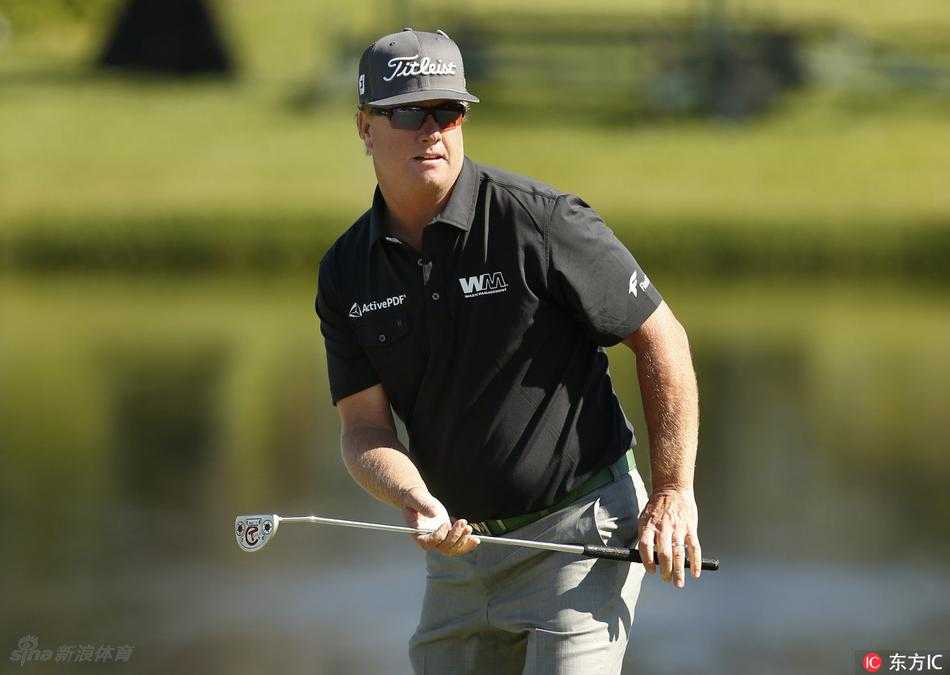 查理-霍夫曼在果岭边凝神观察推击线路，专注的神情预示着他对领先位置的志在必得