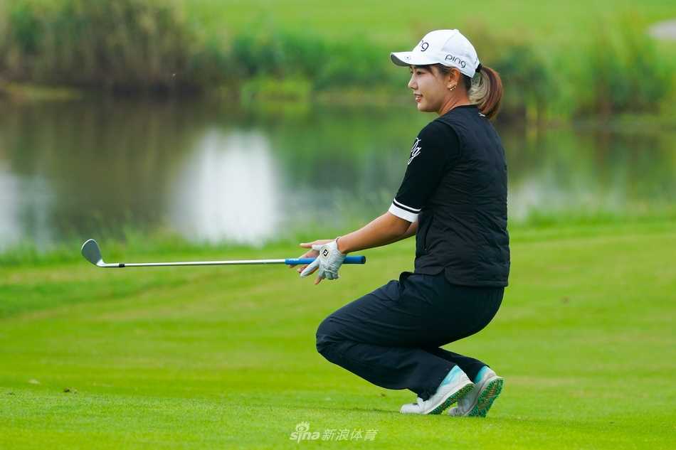 潘艳红手持奖杯与赛场旗帜同框，身后是珠海东方高尔夫球会的美丽果岭