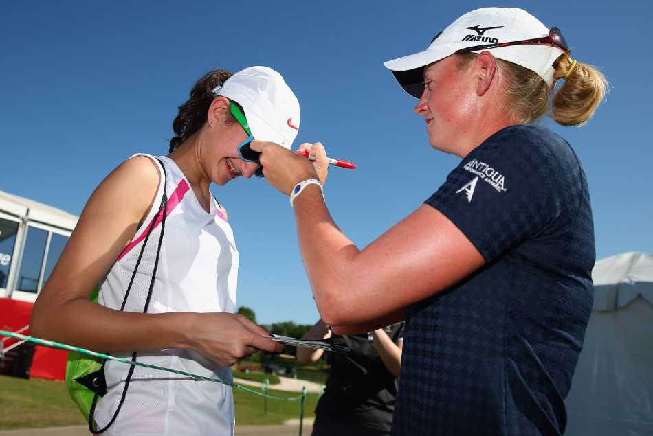 魏圣美面带微笑，俯身亲切地为守候在围绳边的球迷签名，展现了顶尖运动员的亲和力。