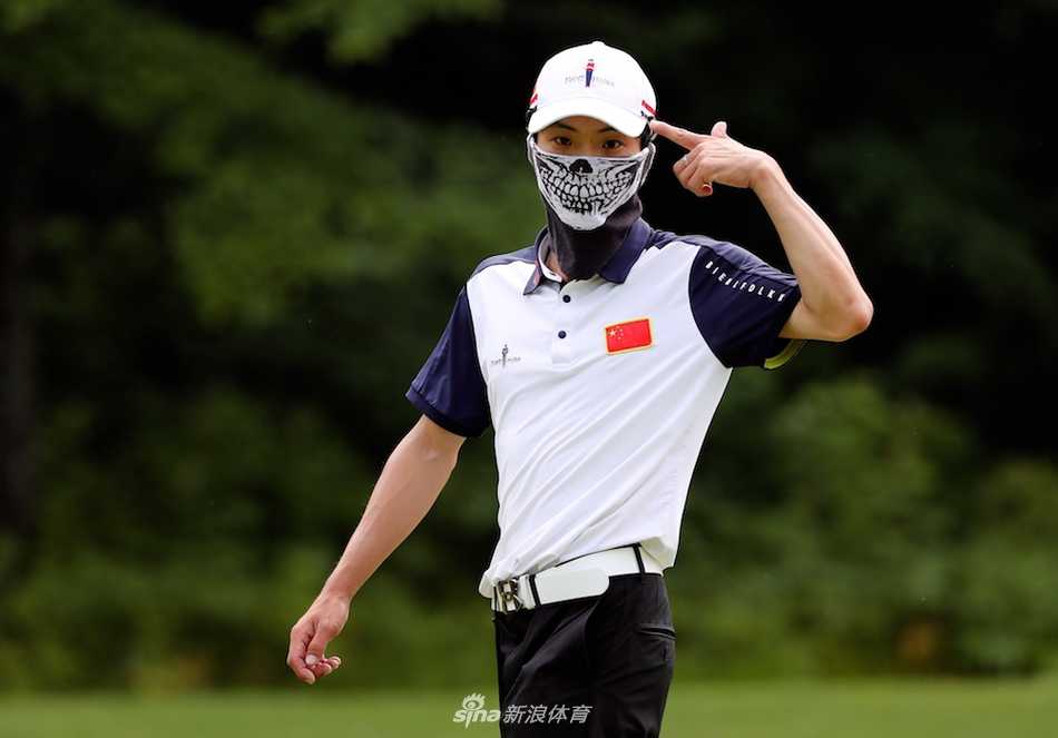 莱安瑞向远方观众挥手微笑，身后是绵延起伏的经典高尔夫球场美景