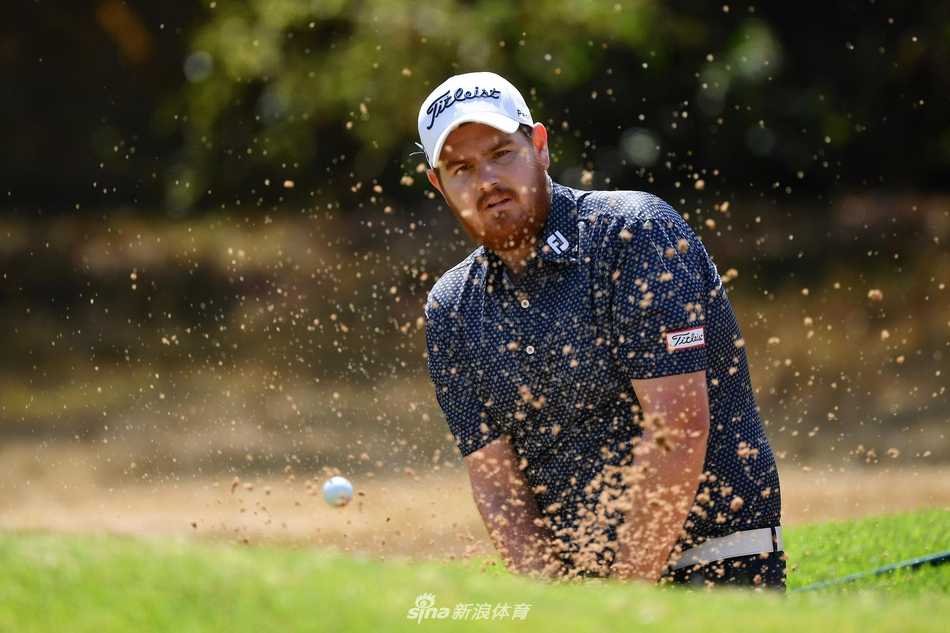 托马斯-比约恩在开阔的球道上潇洒挥杆，背景是经典的林克斯风格球场，风与云在流动。