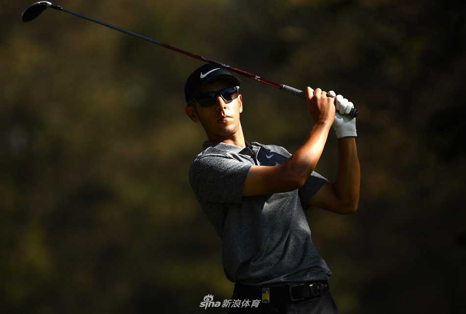 杰克-辛格-布拉尔屏息凝神，在果岭边观察草纹走向，阳光勾勒出他专注的侧影。