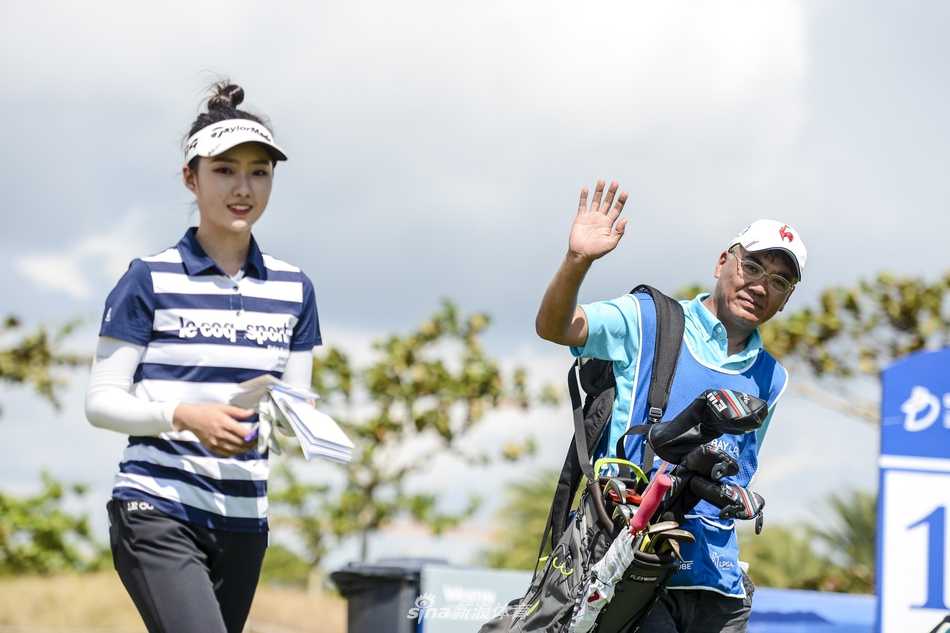 绿茵场上，一位父亲正专注地为女儿擦拭高尔夫球杆，目光中满是呵护与期待。