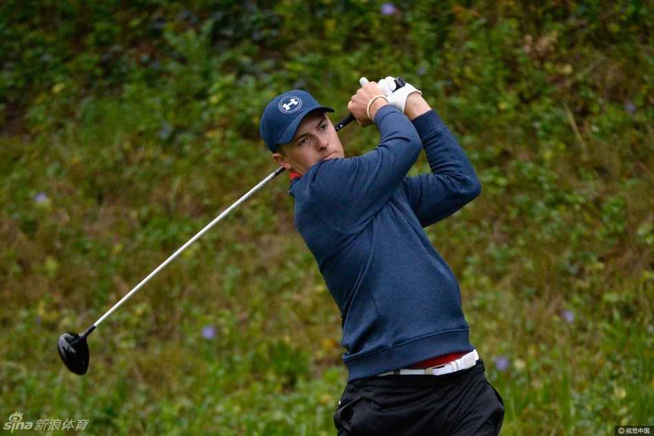 观众们穿着五彩的雨衣，聚集在球道旁的山坡上，如同风雨中绽放的花朵，坚守着观看比赛的执着。