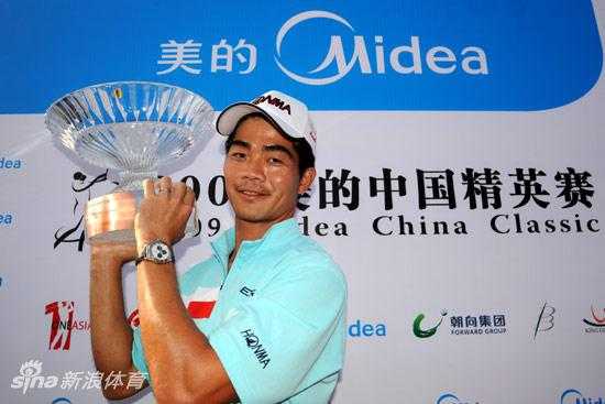 梁文冲在果岭边沉稳推杆，背景是开阔的球场和专注的观众。