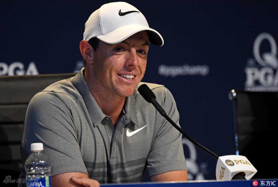 麦克罗伊在练习果岭上屈膝俯身，目光如炬地凝视着小白球与球洞之间的线路