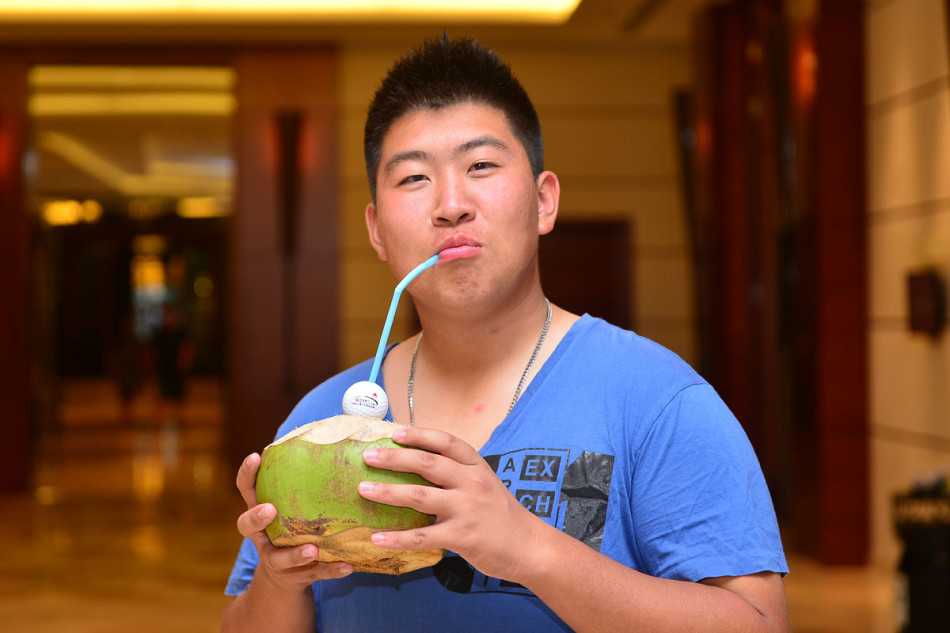 女球员优雅挥杆，白色球帽下神情专注，身后是开阔的蓝天与整齐的果岭