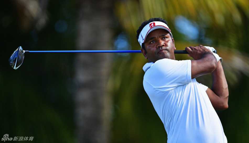 王情训在果岭边细致观察推杆线路，神情专注，身后是典型的岛屿风光