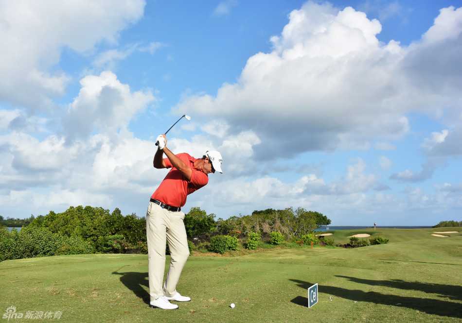 斯迪库尔全神贯注推杆，果岭背景是毛里求斯连绵的苍翠山峦与低压的云层，氛围宁静而紧张