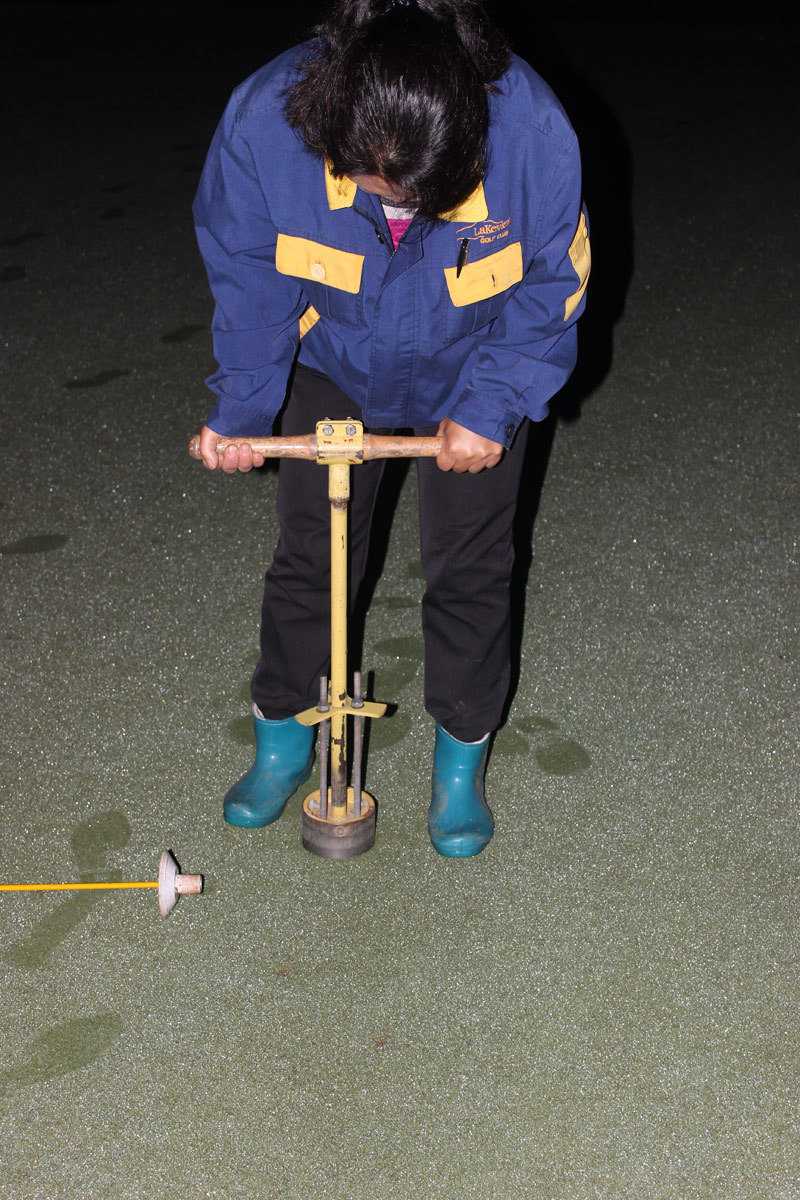 破晓时分的高尔夫球场养护交响曲 工作人员正操作着专业果岭打孔机,机器所过之处,在如绿毯般平整的草坪上留下一排排整齐划一的小孔,这是草坪深呼吸的通道。