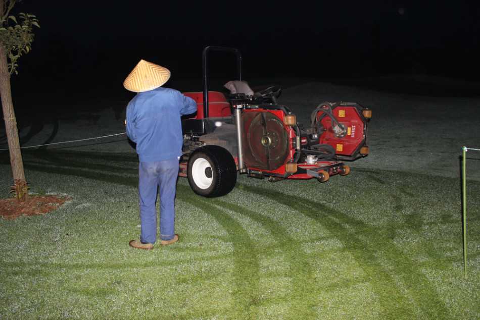 破晓时分的高尔夫球场养护交响曲 晨曦中,草坪养护员正驾驶着专业果岭剪草机,沿着精确的直线缓缓前行,身后留下深浅交替的完美条带,仿佛为大地点染上细腻的条纹织锦。