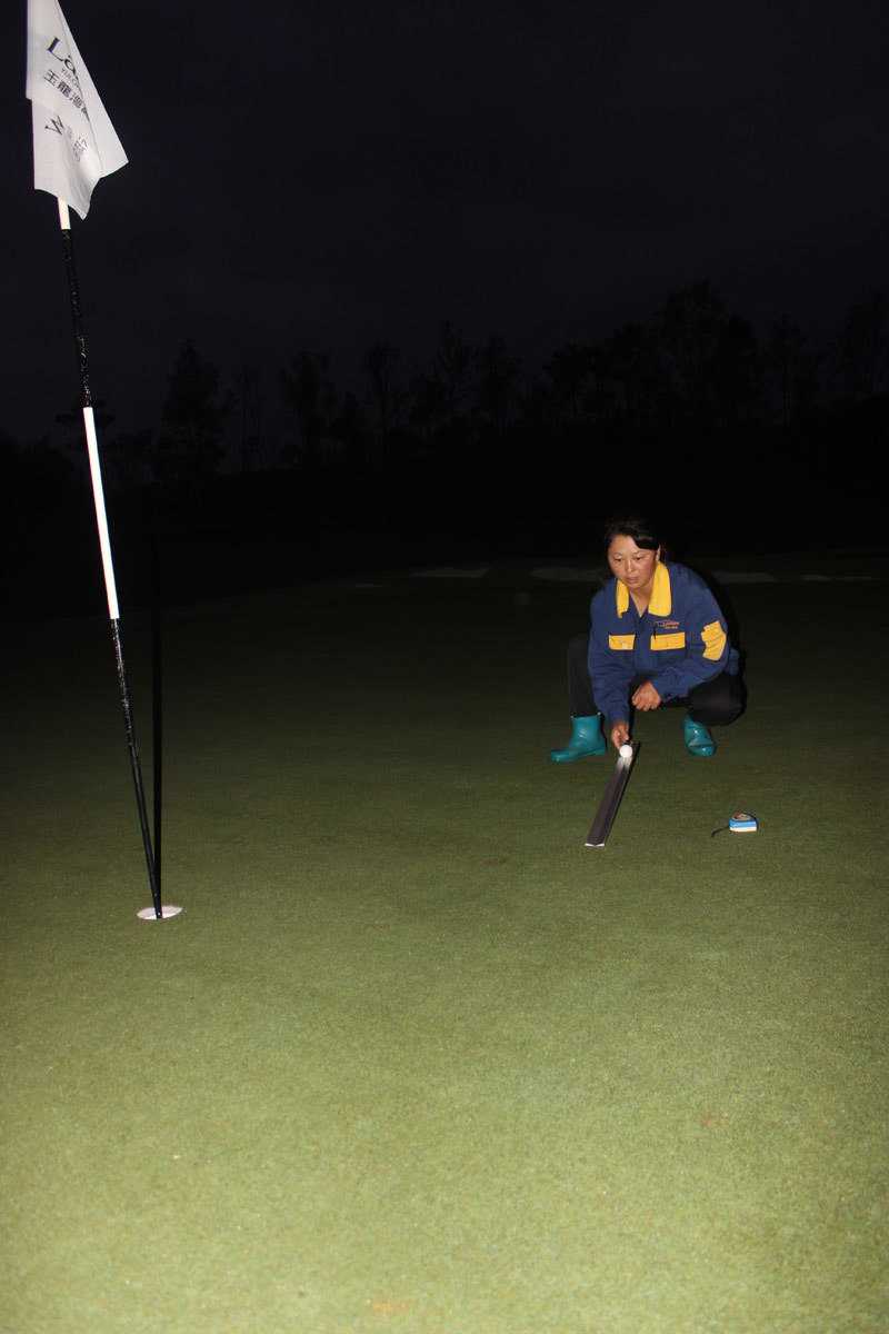 破晓时分的高尔夫球场养护交响曲 一台大型三联式球道剪草机正在宽阔的球道上稳步推进,如同一位巨大的绿色画师,用轮胎和刀片在旷野上绘出磅礴的几何画卷。