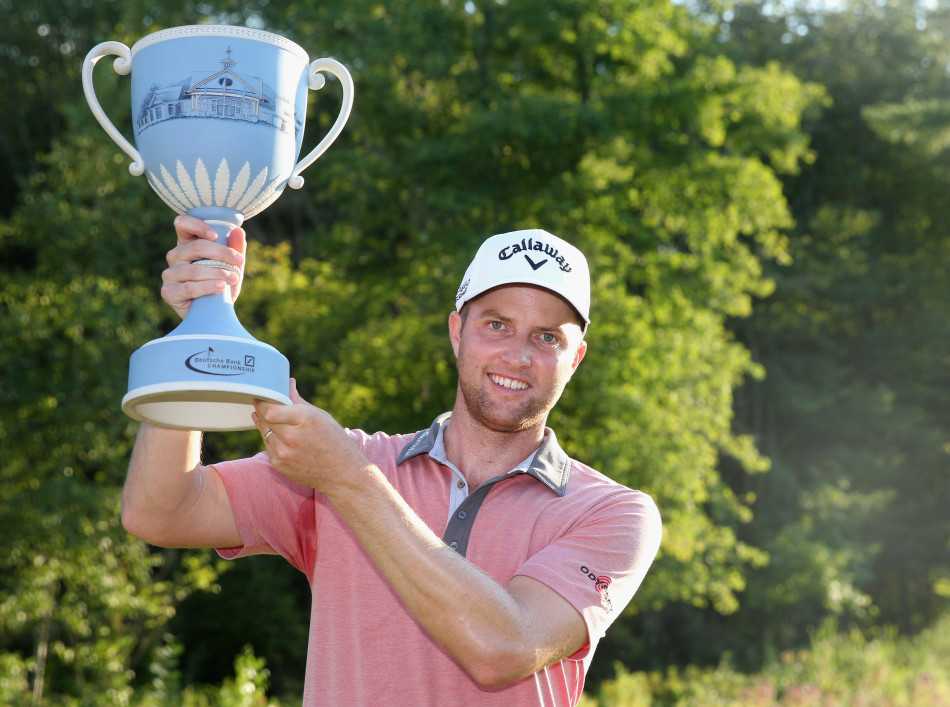 麦克罗伊微微蹙眉，全神贯注地蹲在果岭边分析推杆路线，身旁的球童也凝神注视。