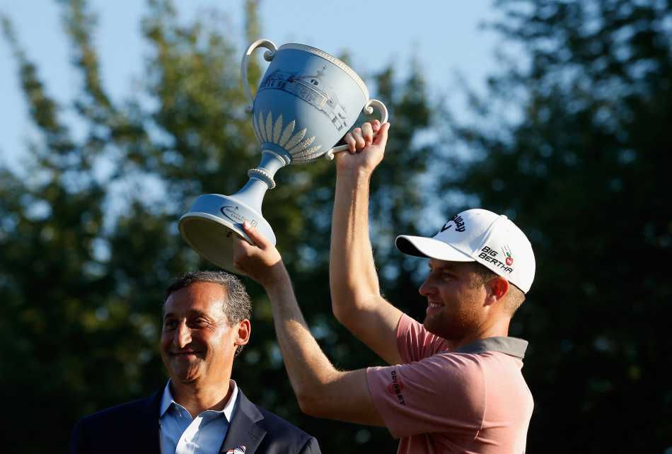 科克弯腰将奖杯递到好奇的孩子面前，小朋友伸出小手轻轻触摸，父子俩脸上洋溢着同样的笑容。