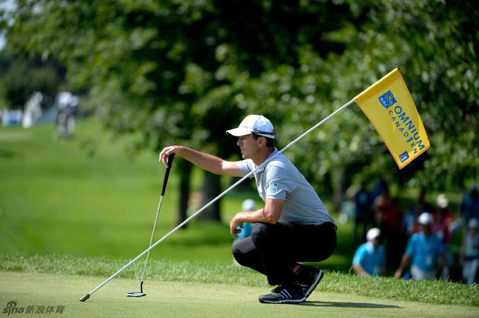 一位球员正专注地背对果岭旗观察推击线路，他的身影在夕阳下被拉长，显得格外认真而孤独。