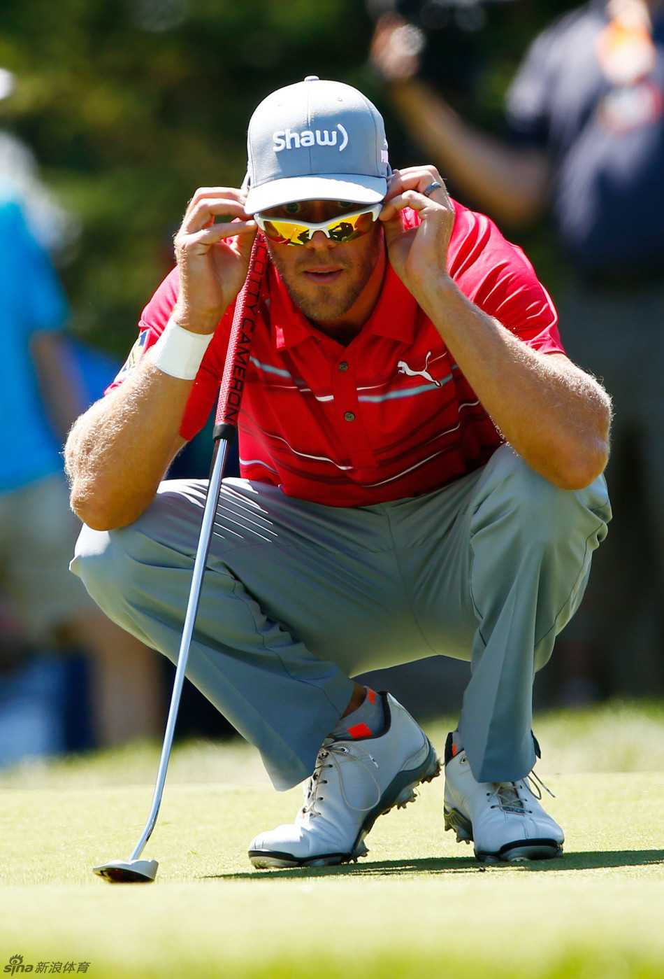 法国球员亚历山大·莱维正单膝跪地，聚精会神地阅读果岭上复杂的坡度与草纹走向。