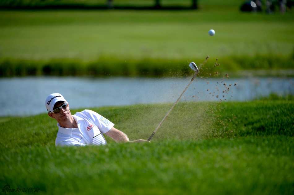 加拿大选手大卫·赫恩在沙坑中准备救球，他身体微微下沉，眼神锐利，正评估着如何将球攻上果岭。
