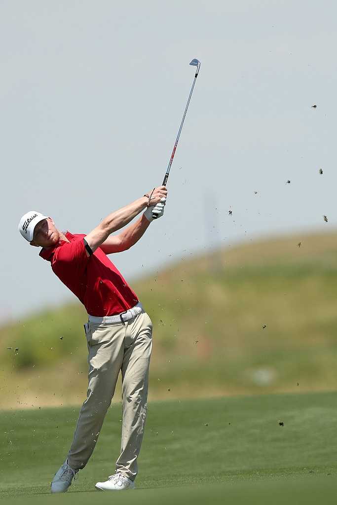 球手在发球台优雅完成收杆动作，目光坚定追随着空中飞行的小球轨迹