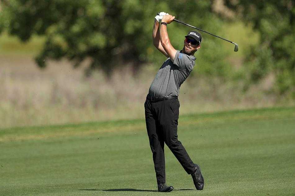 冠军级球员在果岭上沉稳推击，背景是巍峨连绵的落基山脉轮廓