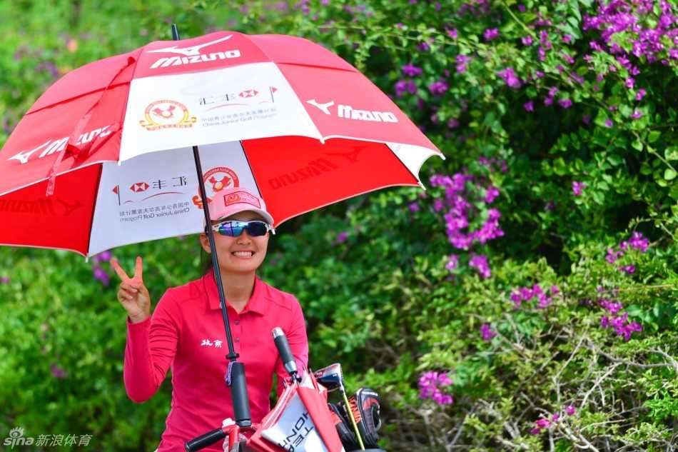 北京一队的杜默涵在果岭边展露甜美笑容，阳光与绿草映衬着她的自信与快乐。