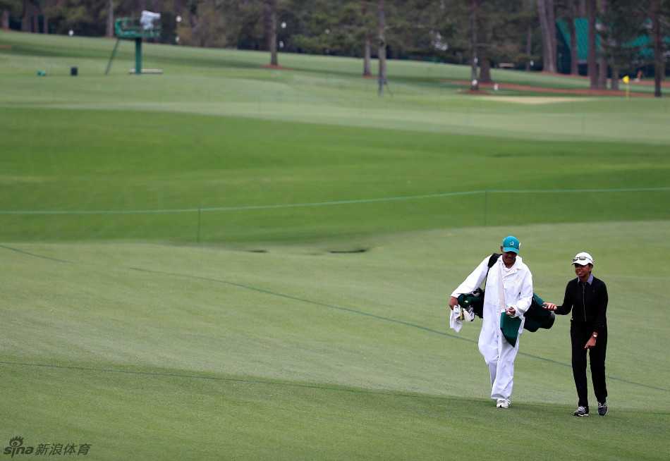 父亲在练习果岭上温柔指导年幼儿子推杆，阳光洒在父子专注的脸庞上
