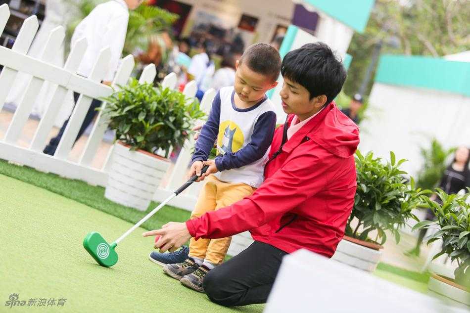 公众互动区内小朋友们正在趣味高尔夫游戏设施上玩耍，一人挥杆，众人围观，充满童趣。