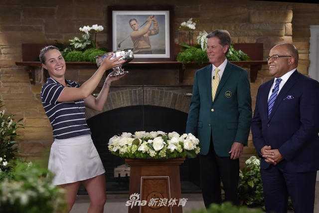 冠军奖杯在奥古斯塔的阳光下熠熠生辉，被一位赛事工作人员庄严捧起，等待献给当日的胜利者，象征着荣耀与传统的传递。