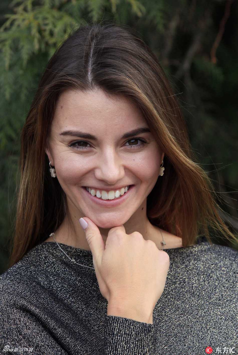 斯皮尔科娃一袭优雅风衣，背靠布拉格古典建筑的石墙，手持铁杆展露从容浅笑，古典与现代在此刻完美交织。