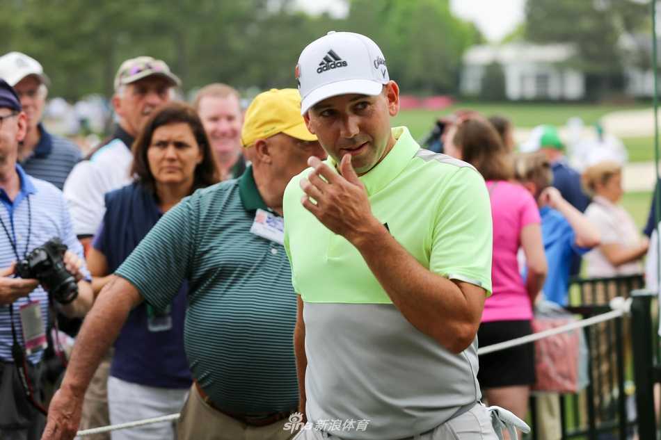著名球手在练习轮中凝神推杆，身后苍翠松林与湛蓝天空构成宁静背景，帽檐下目光如炬