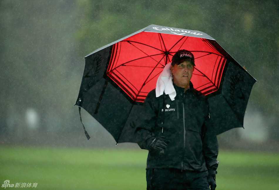 米克尔森在临时雨棚下与同组球员轻松交谈，面对天气干扰从容不迫。