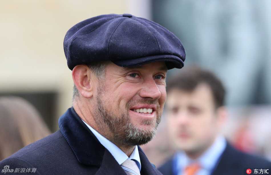 维斯特伍德收敛笑容，神情专注地望向赛场方向，似乎正在紧张地关注着比赛的进程，手中或许还握着一份下注单。