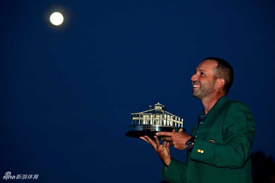 上届冠军丹尼·威利特面带微笑，正仔细地为新科大师赛冠军加西亚穿上那件梦寐以求的墨绿色夹克