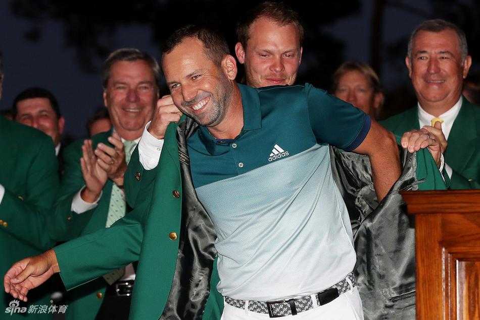 加西亚独自站立，深情地低头凝视着刚刚穿在身上的绿夹克，手指轻抚面料，仿佛在确认梦想已成现实