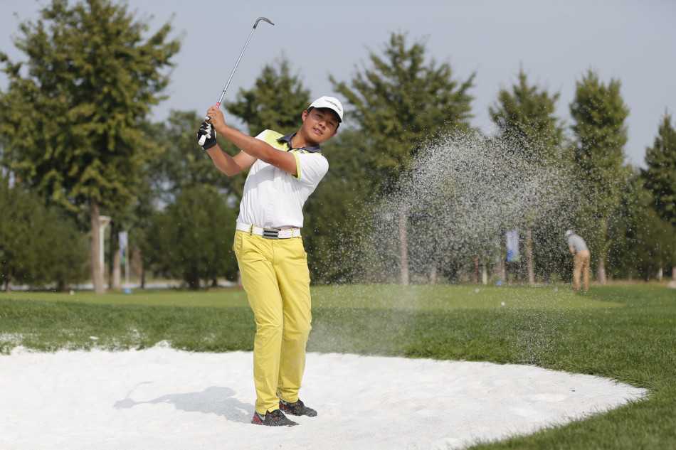 一位小球员在阳光下凝神静气，正做出标准的挥杆击球动作，白色的高尔夫球在空中划出一道优美的弧线。