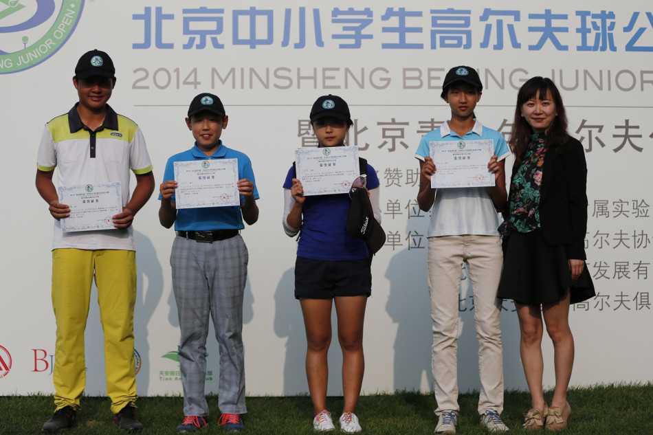 颁奖仪式现场，获奖的小球员们整齐排列，高举奖杯与鲜花，背景板上清晰展示着赛事荣誉，气氛热烈而隆重。