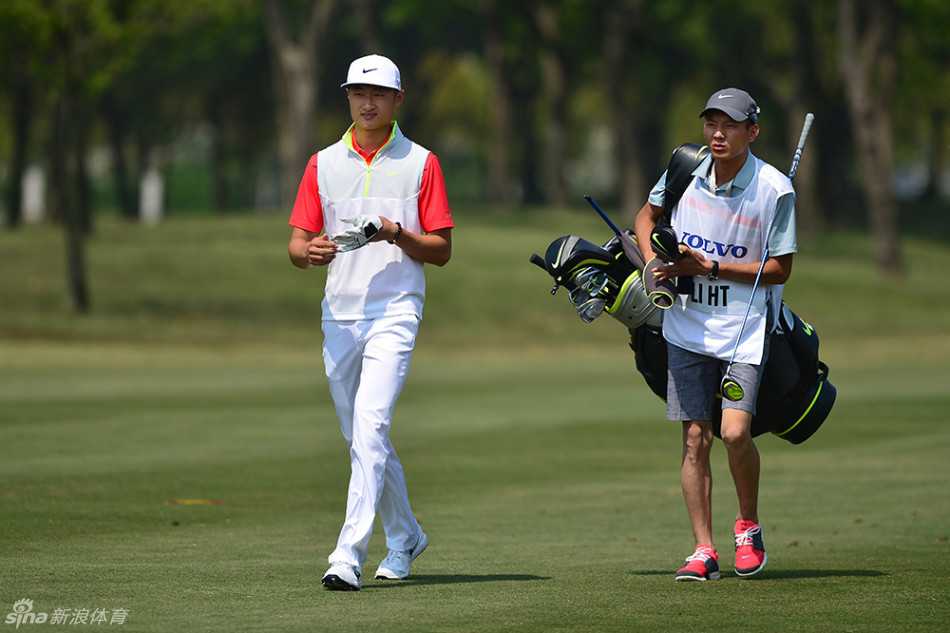 帅气的高尔夫球手吴阿顺正低头仔细研读手中的码数本，在果岭边为关键一击做最后的精密计算。