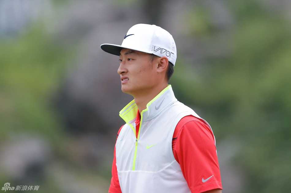 李昊桐与身旁的球童正在紧张地商讨策略，两人目光聚焦于手中的球杆，为接下来的挑战做好准备。