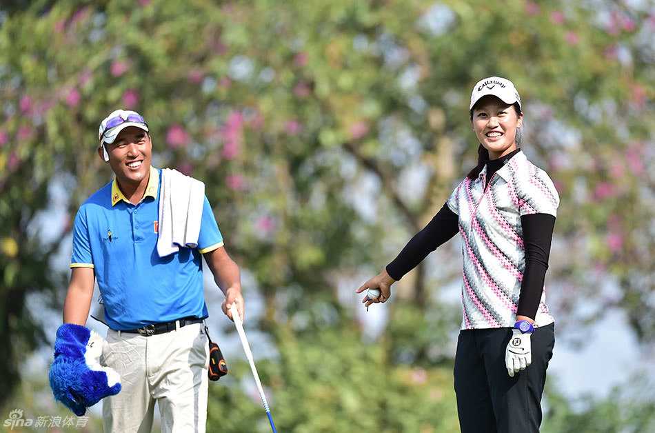 石昱婷与球童在果岭边俯身观察，专注商讨推击线路与策略