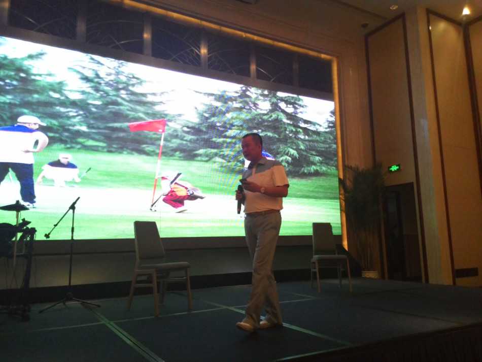 会长连卓明为净杆冠军颁发闪亮奖杯，两人握手 congratulation，背景是掌声雷动的会场