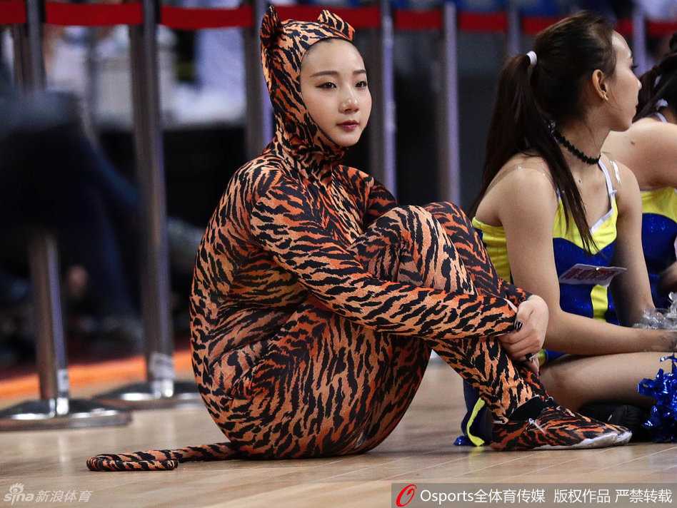 一位身穿狂野豹纹套装的长发啦啦队员，正随着动感音乐扭动身体，眼神自信地看向镜头，展现出迷人的赛场风采。