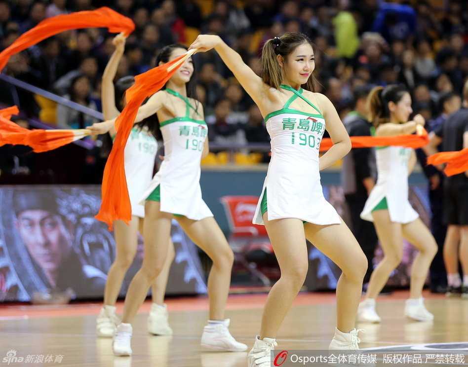 赛场边的篮球宝贝跪地热舞，动作妩媚动人，眼神充满感染力，与身后专注比赛的球员形成动静皆宜的画面。