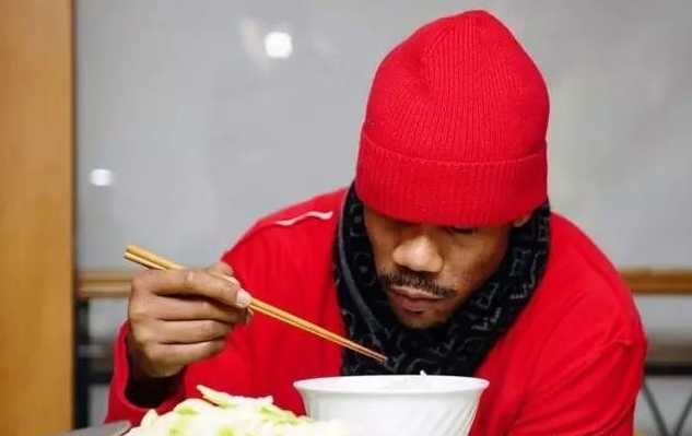 一位外国友人正全神贯注地用筷子夹起美食，脸上洋溢着自信和满足的微笑