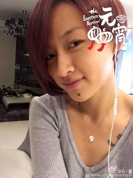 身穿休闲深色上衣的石一童单手轻扶墙面，侧颜线条堪称完美，下颌线精致流畅，展现出一种介于女孩的柔美与运动员的帅气之间的独特气质。