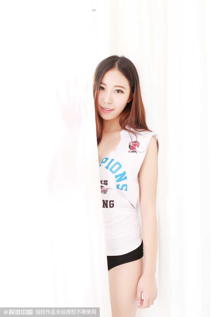 镜头特写女孩回眸的瞬间，长发飘飘，眼神清澈而坚定，她身穿的15号球衣在灯光下显得格外醒目，仿佛象征着为球队贡献百分之百的力量。