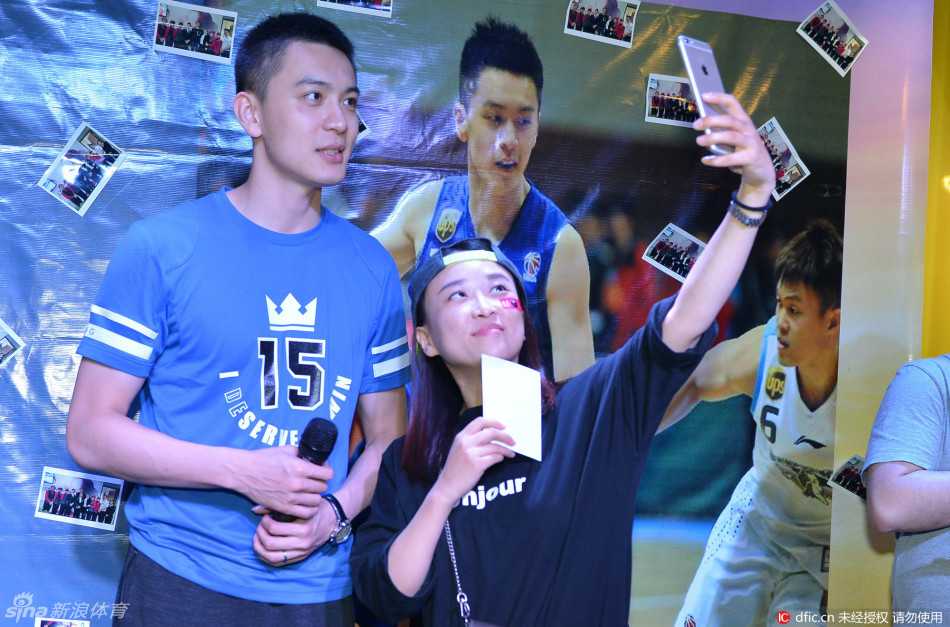 在精心布置的签名海报墙前，杨鸣手执球迷递上的珍贵照片，眼神专注而温柔，正准备签下自己的名字，将这瞬间的相逢化作粉丝永恒的珍藏。