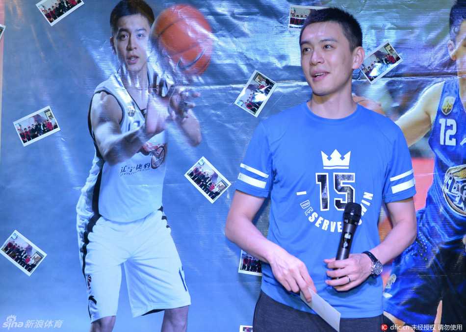 杨鸣帅气地单手插兜，正与一位年长的忠实球迷握手交谈，他的身体微微前倾，以示尊重，面容上带着谦逊而温暖的笑意，毫无明星架子。